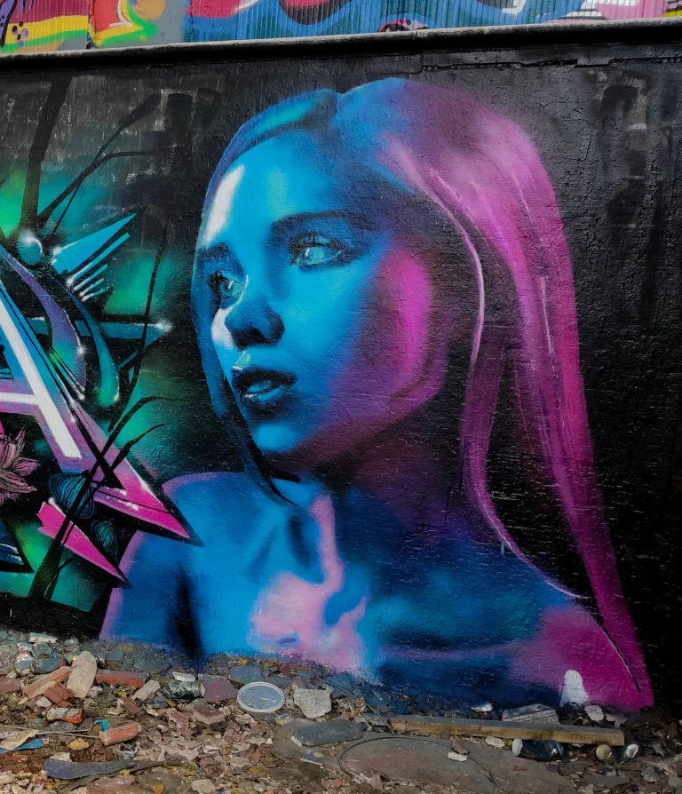 Graffiti mural of a girl with long pink hair in blue and magenta light